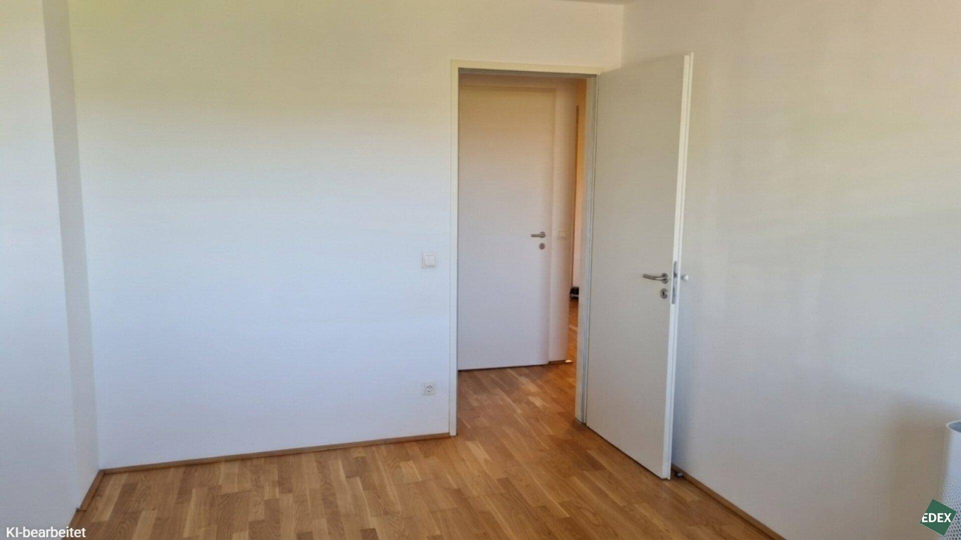 Leerer Raum mit hellem Parkettboden und weißen Wänden, bereit zur individuellen Gestaltung.