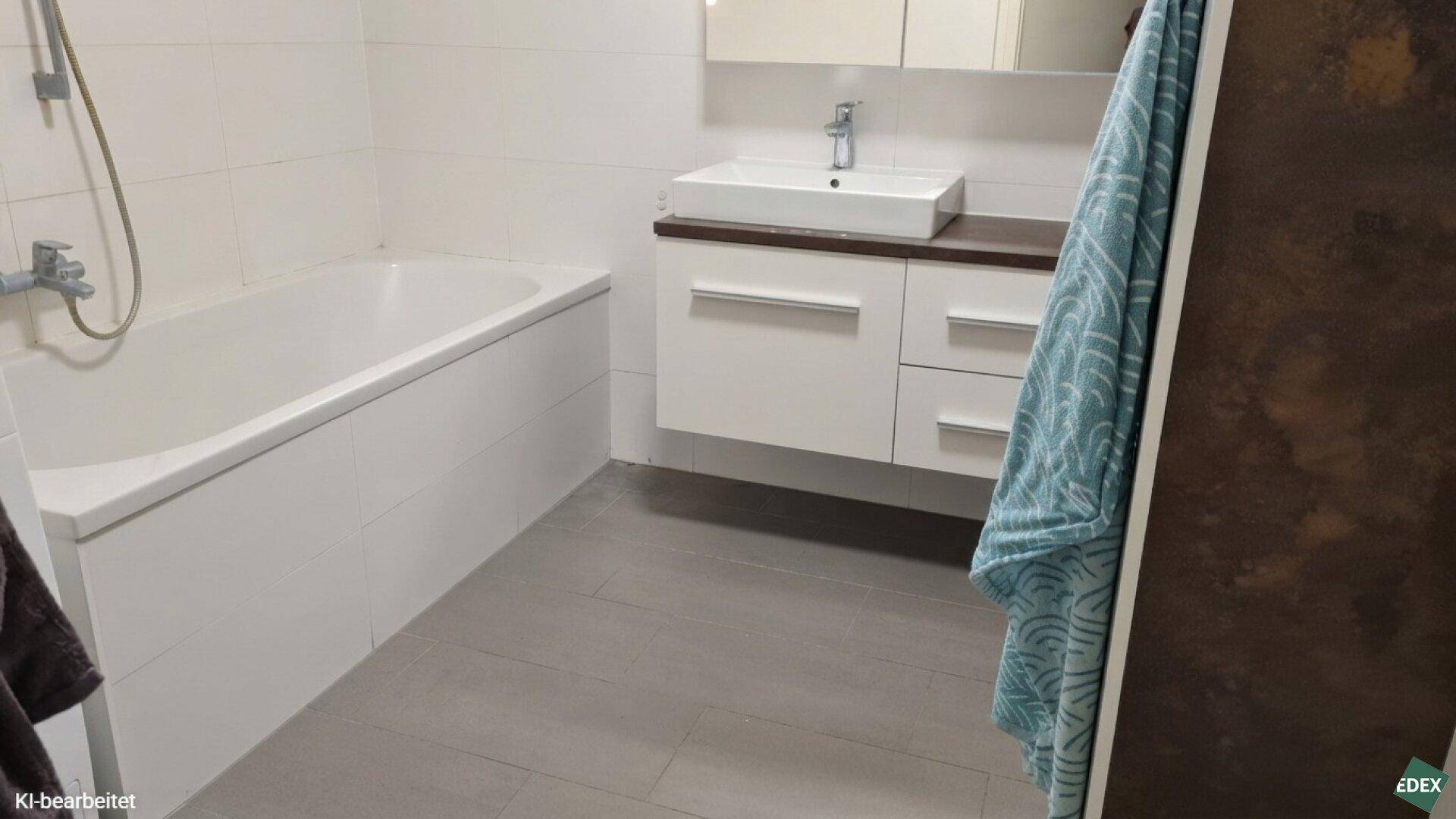 Modernes Badezimmer mit Badewanne, Einzelwaschbecken und hellen Fliesen an Wänden und Boden.