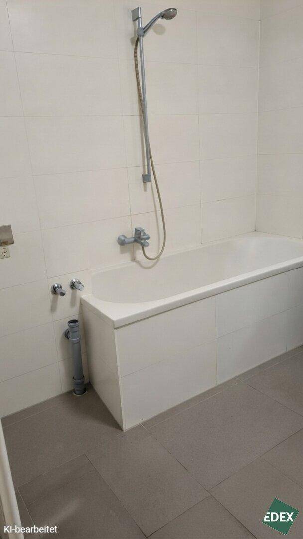Detailansicht der Badewanne mit integrierter Duschfunktion und hellen Wandfliesen.