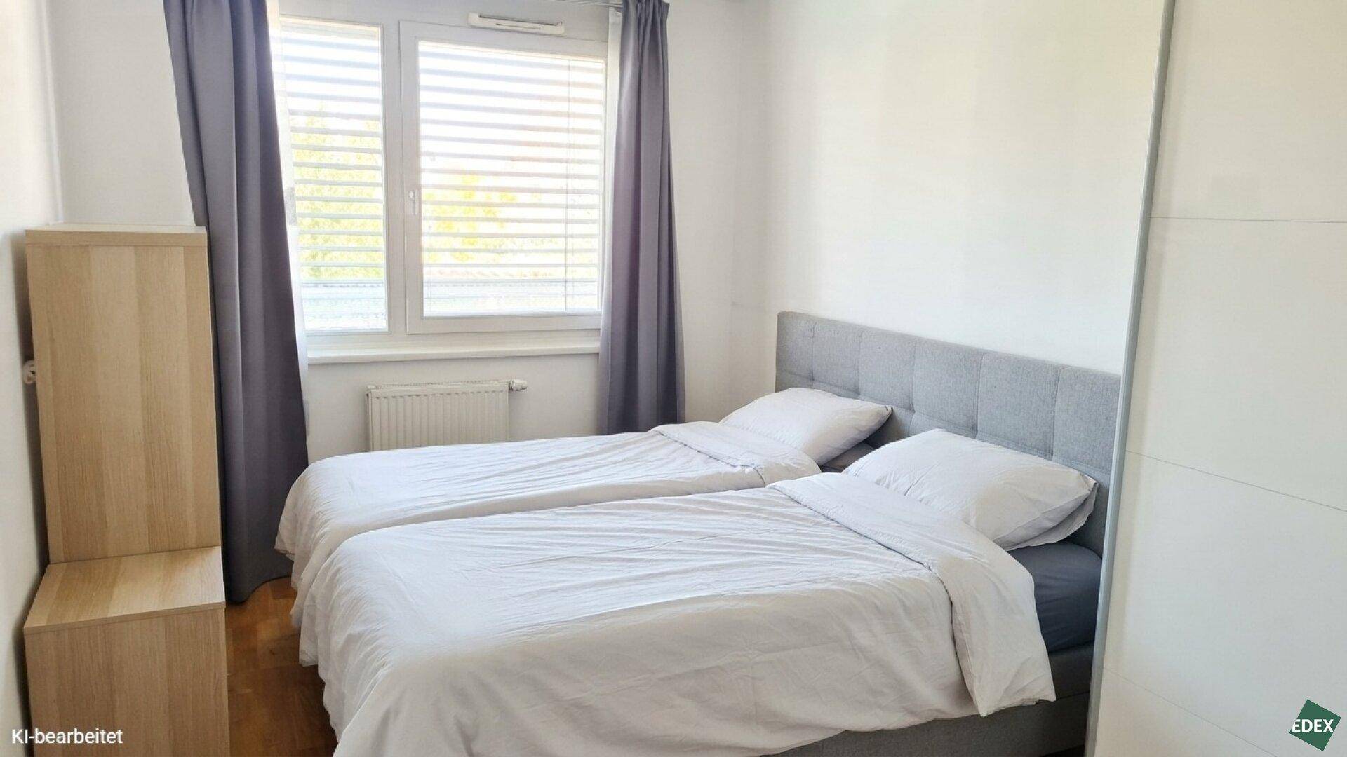 Helles Schlafzimmer mit zwei Einzelbetten, Fenster mit Jalousien und Holzmöbeln.