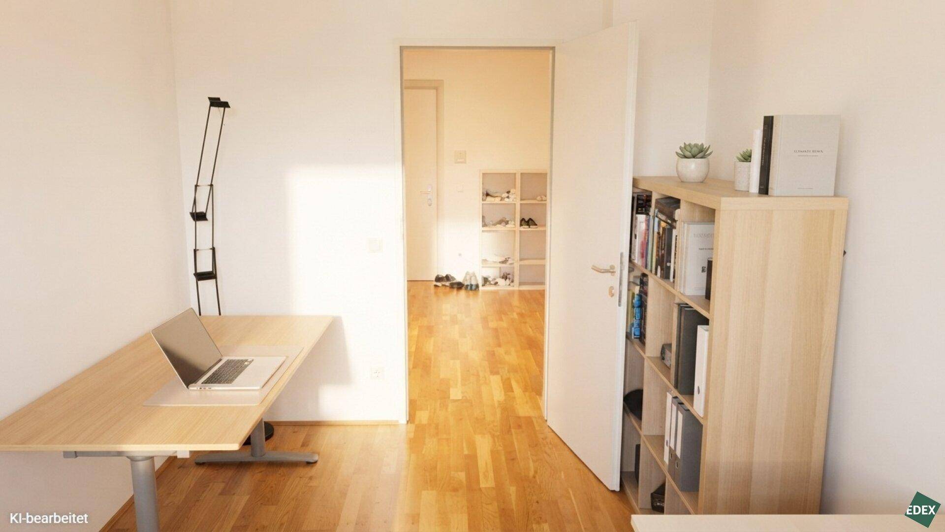 Funktional eingerichtetes Büro mit Schreibtisch, Laptop und Bücherregal, angrenzend an einen Flur.