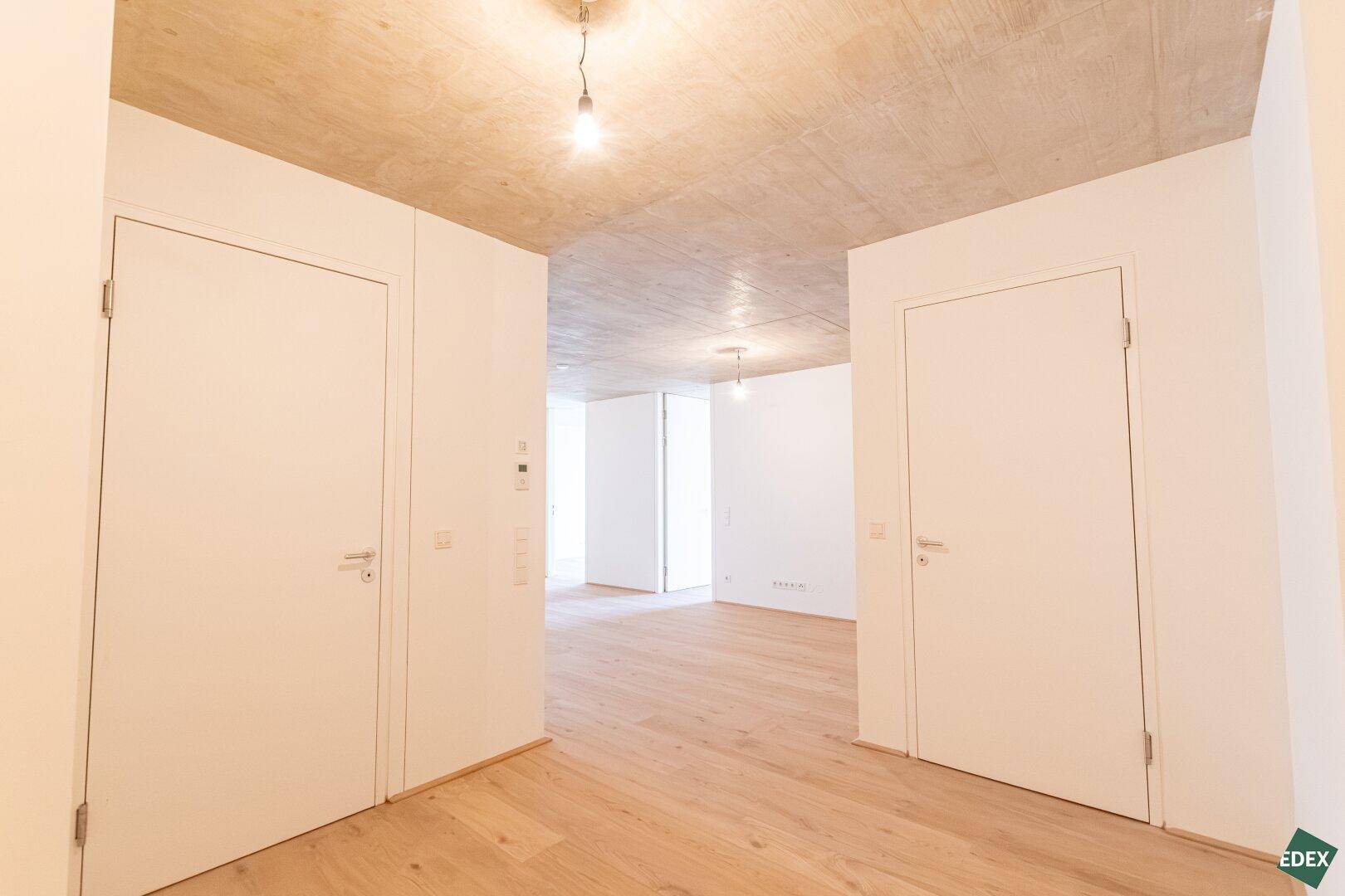 Heller Flurbereich mit Holzboden, weißen Wänden und mehreren Türen, der verschiedene Räume verbindet.