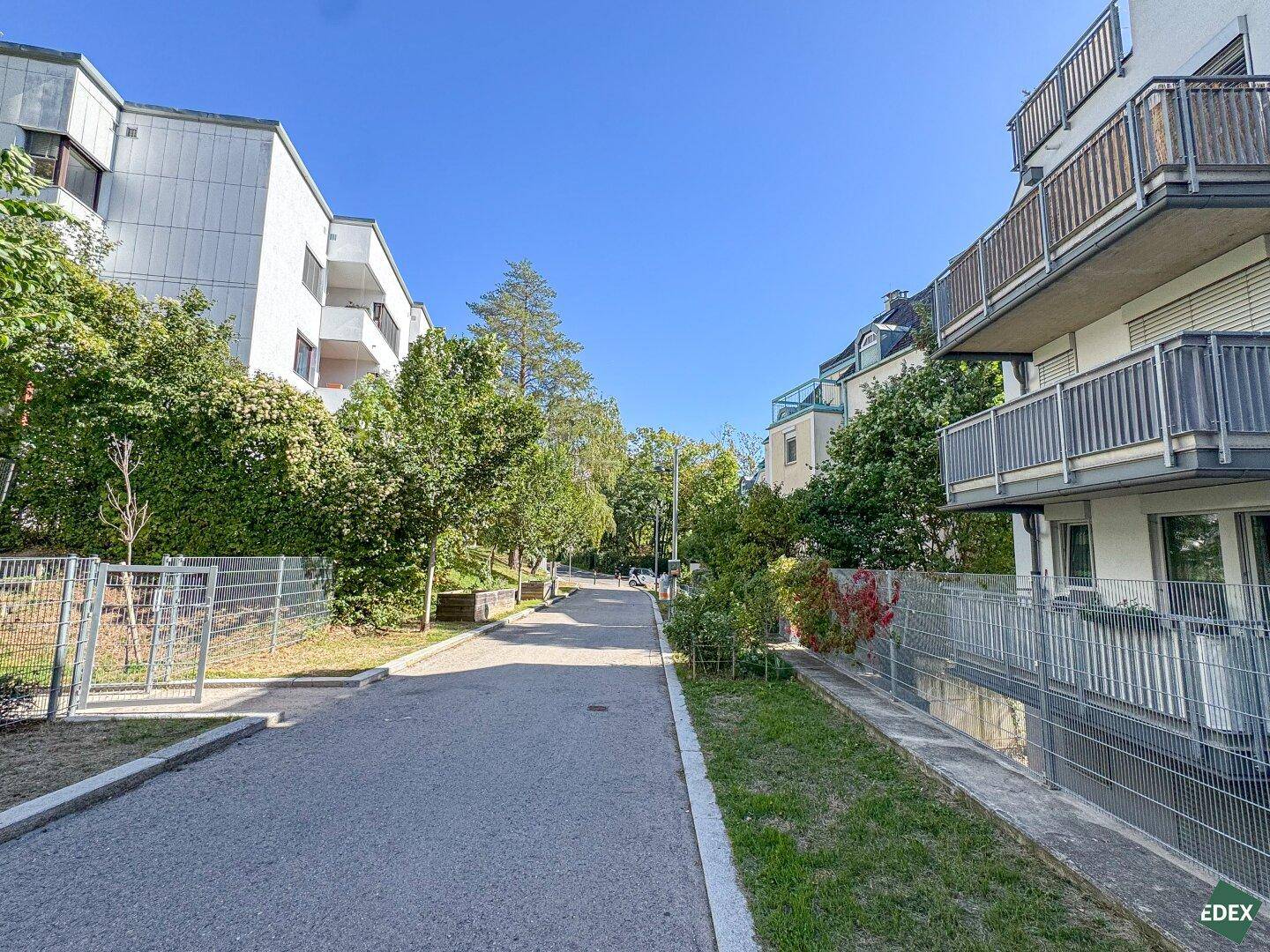 Wohngegend mit begrünten Wegen und modernen Gebäuden, die Balkone aufweisen.