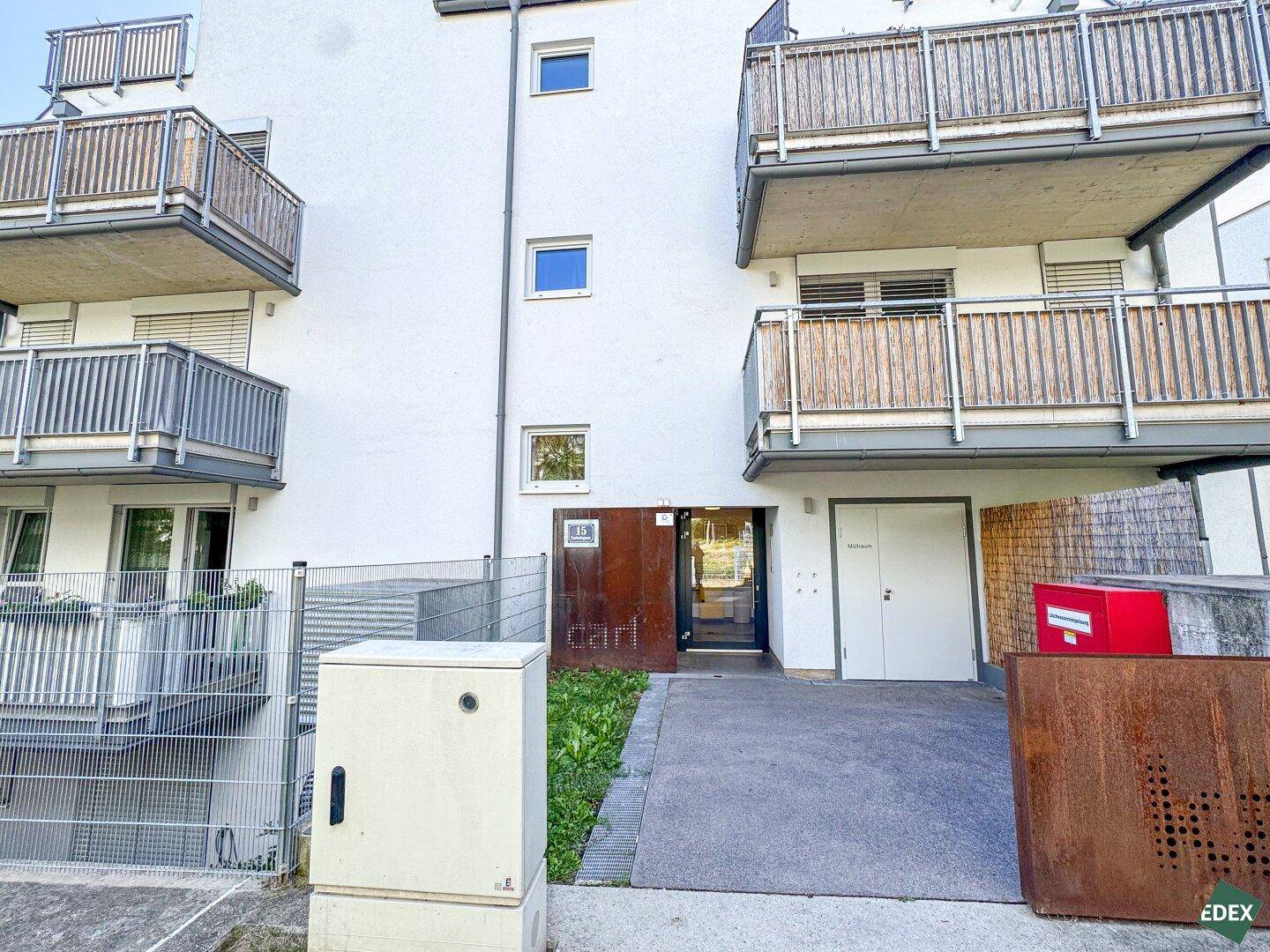 Eingangsbereich eines modernen Mehrfamilienhauses mit Balkonen und Außenanlagen.