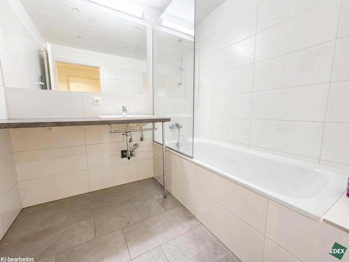 Modernes Badezimmer mit weißen Fliesen, Badewanne mit Duschabtrennung und Einzelwaschbecken.