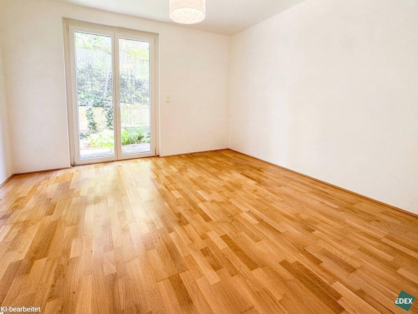 Helles Schlafzimmer mit Holzboden und großen Fenstertüren, die viel Tageslicht hereinlassen.