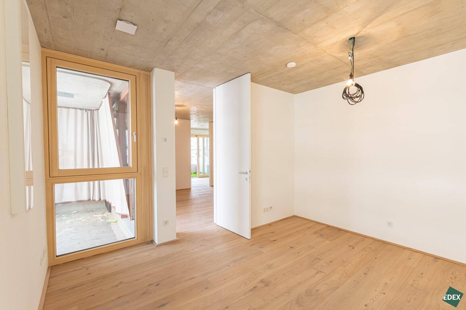 Heller Raum mit Holzboden und Zugang zu einem Außenbereich, ideal für individuelle Gestaltung.