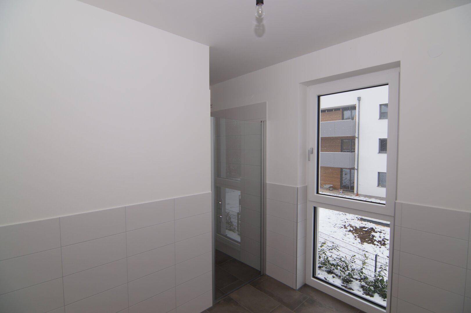 Modernes Badezimmer mit Duschkabine, Fliesenboden und Fenster für natürliche Belüftung.