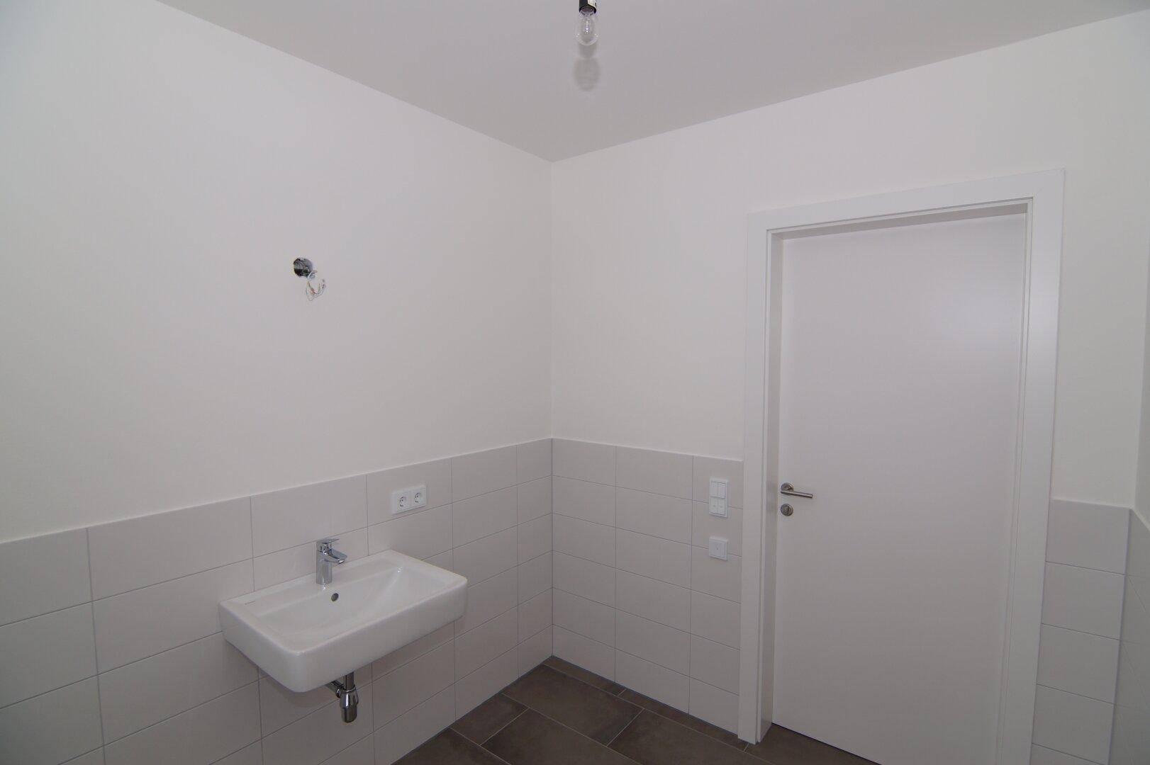 Modernes Badezimmer mit Einzelwaschbecken und weißen Wandfliesen, in neuwertigem Zustand.