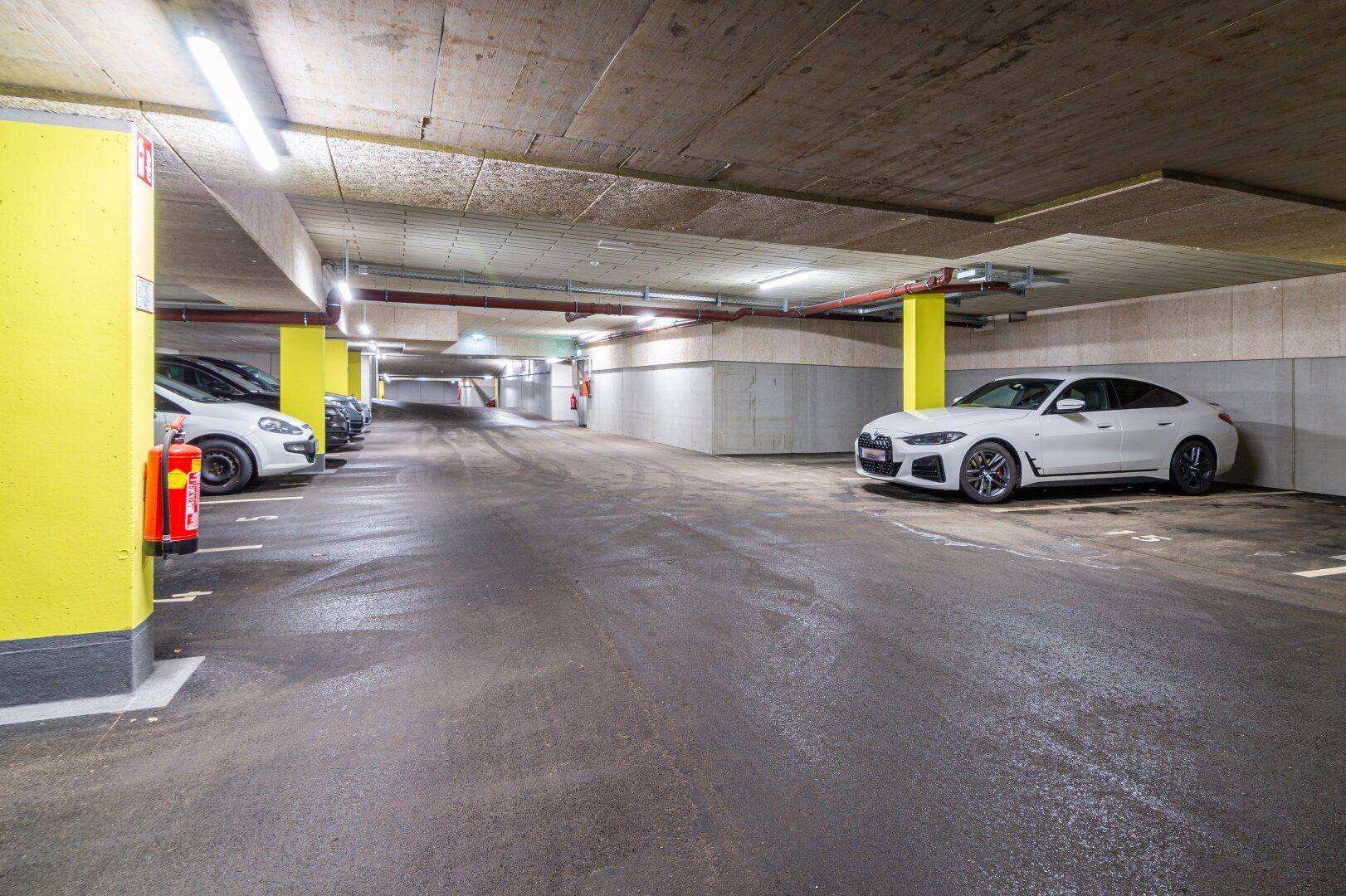 Geräumige Tiefgarage mit vielen Stellplätzen, hellen Säulen und guter Beleuchtung.