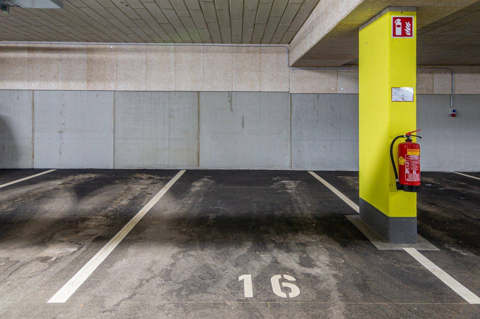 Markierter Stellplatz Nummer 16 in der Tiefgarage mit Brandschutzvorrichtung.