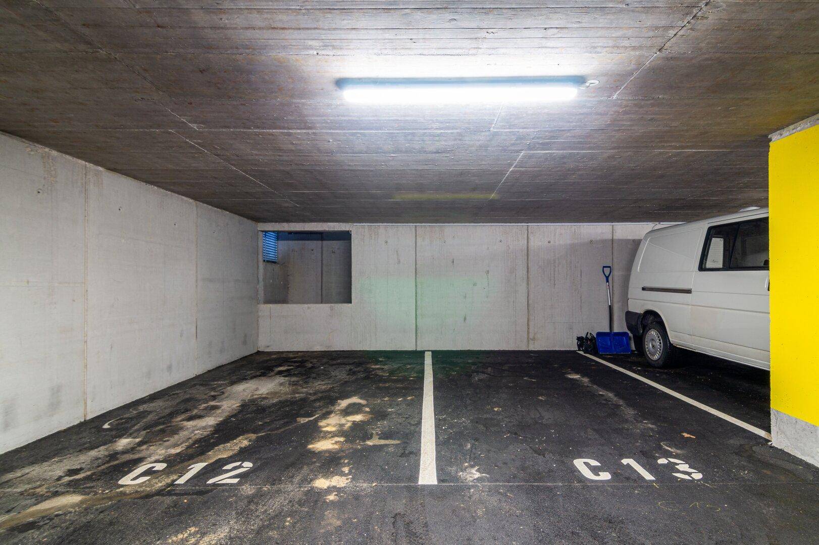 Zwei freie Stellplätze C12 und C13 in der Tiefgarage neben einem Lieferwagen.