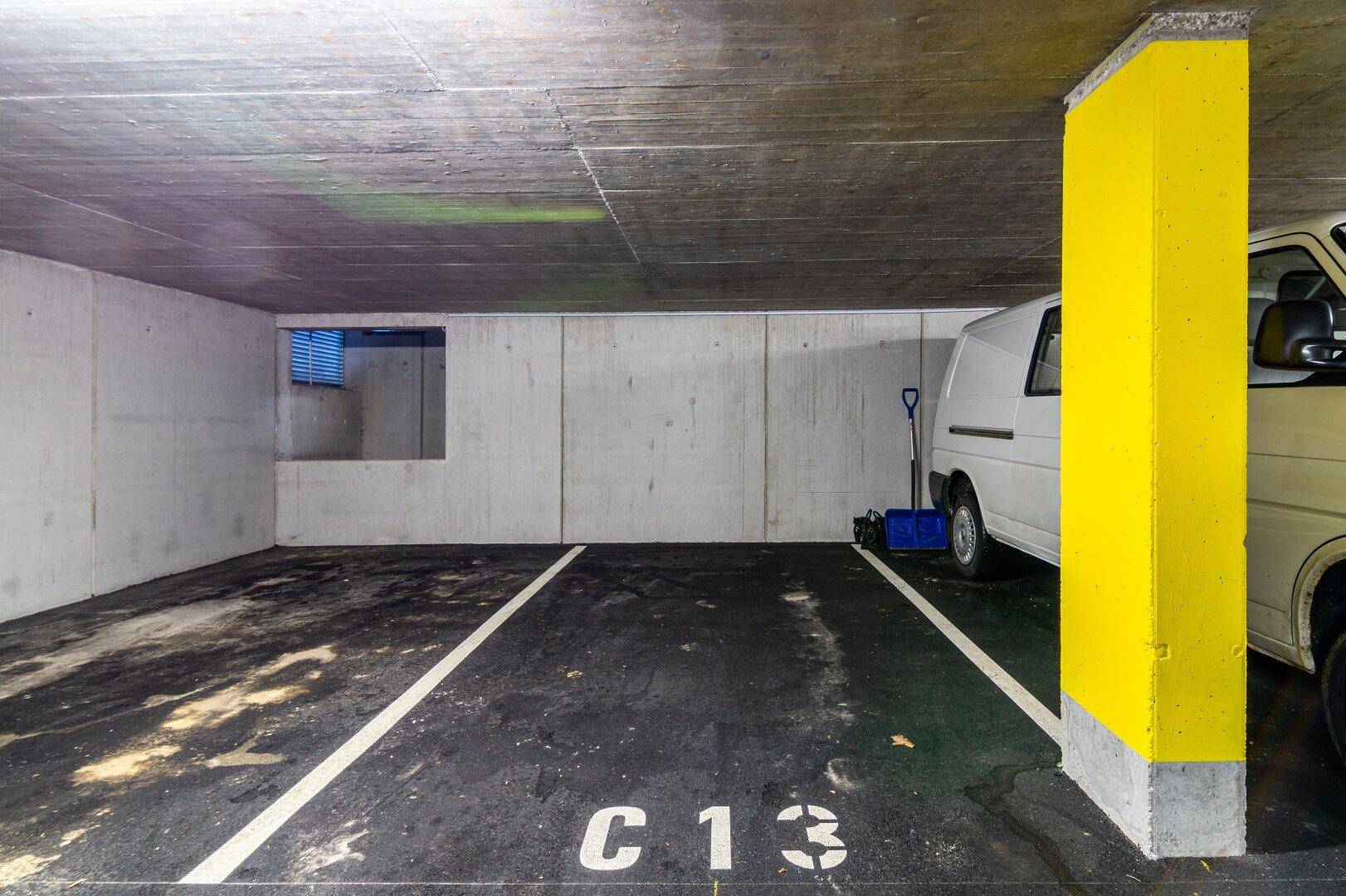 Stellplatz C13 in der Tiefgarage mit gelber Säule und einem geparkten Lieferwagen.