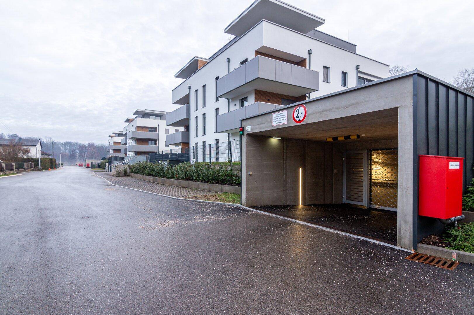 Moderne Wohnanlage mit Tiefgarageneinfahrt und zeitgenössischer Architektur.