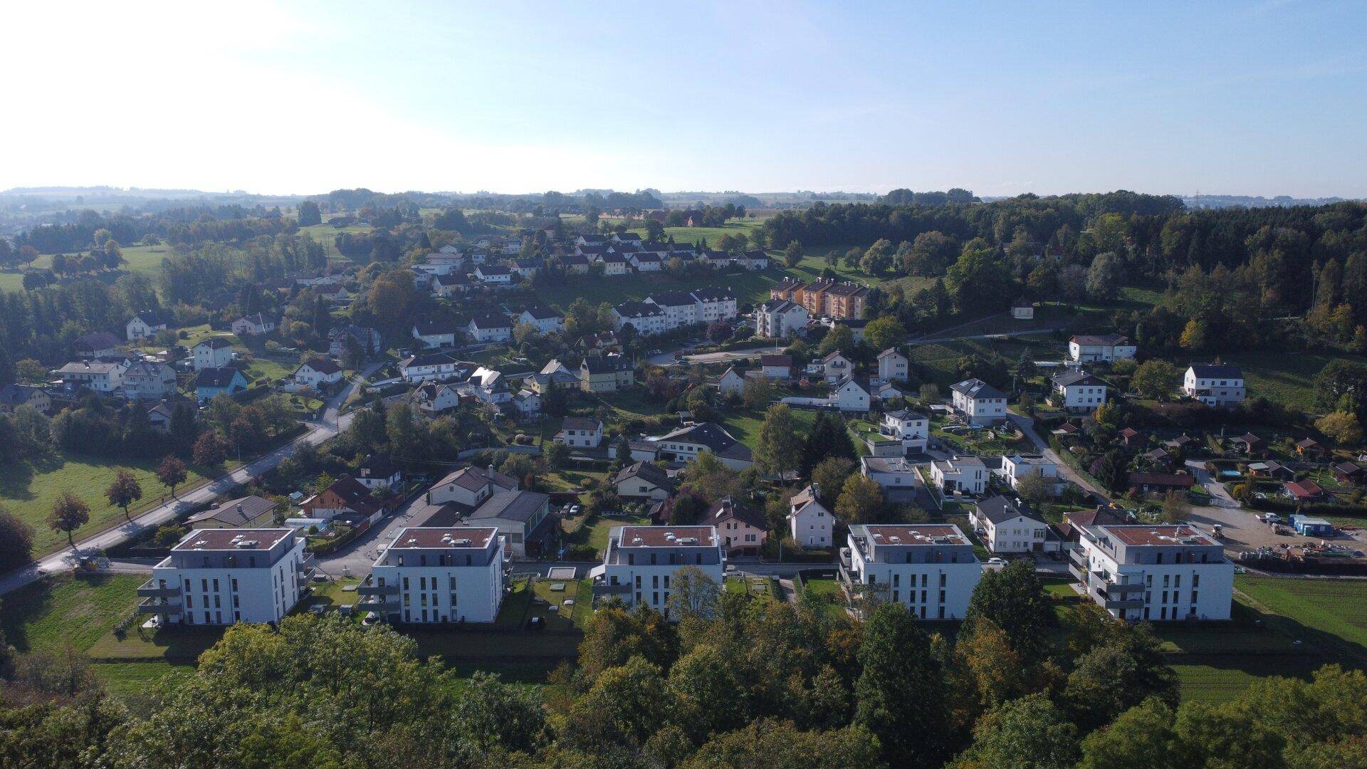 Luftaufnahme einer modernen Wohnsiedlung mit Neubauten und viel Grün in ländlicher Umgebung.