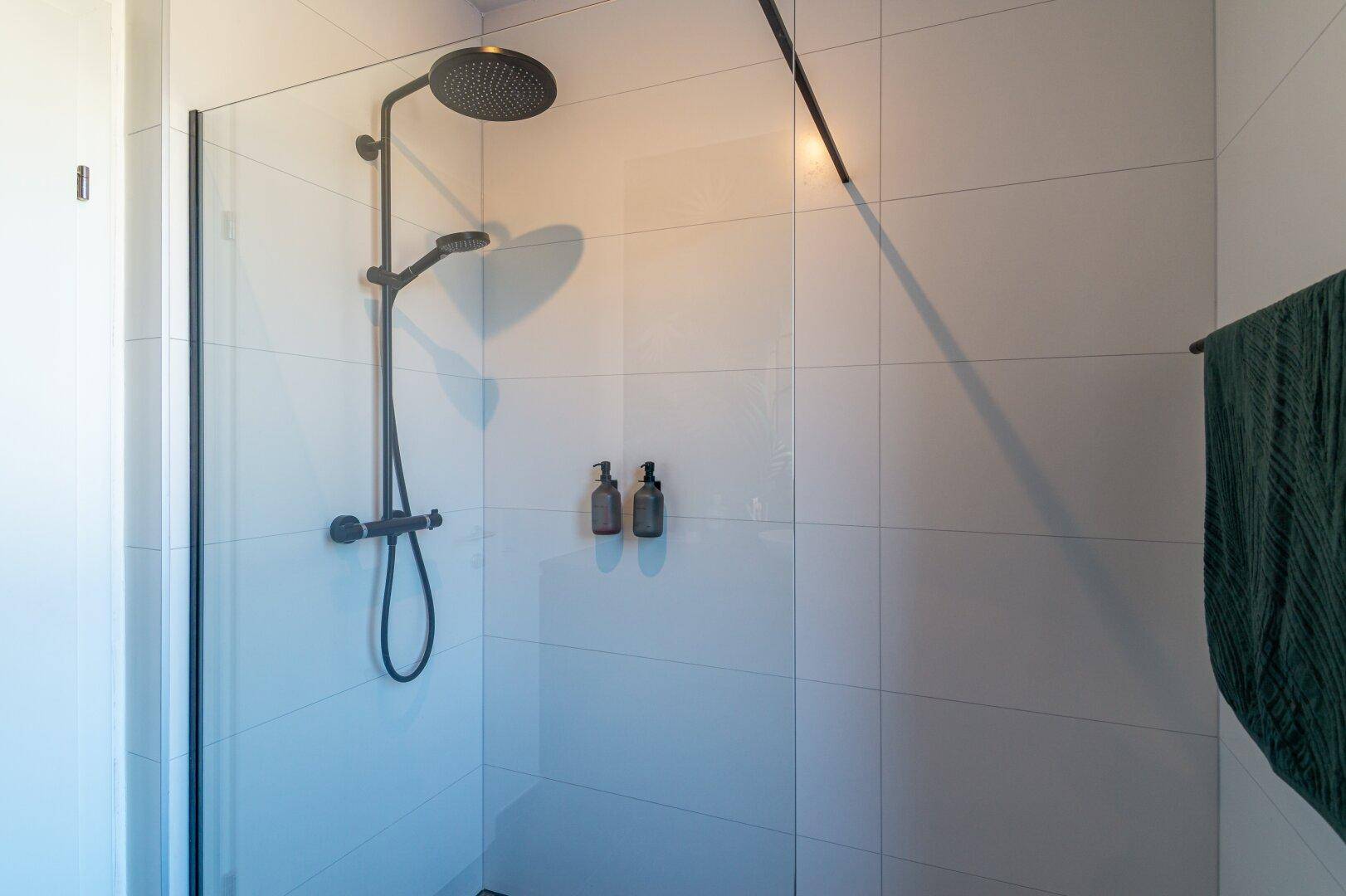Moderne Duschkabine mit Regendusche und weißen Fliesen im Badezimmer.
