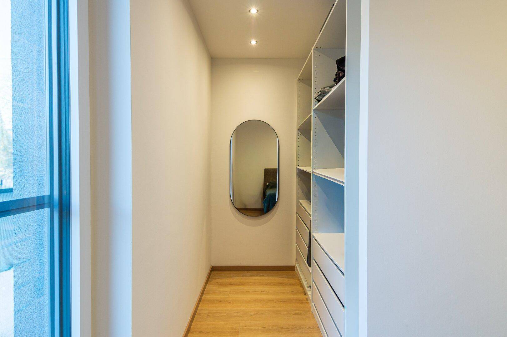 Praktischer begehbarer Kleiderschrank mit Regalen und Spiegel für zusätzlichen Stauraum.