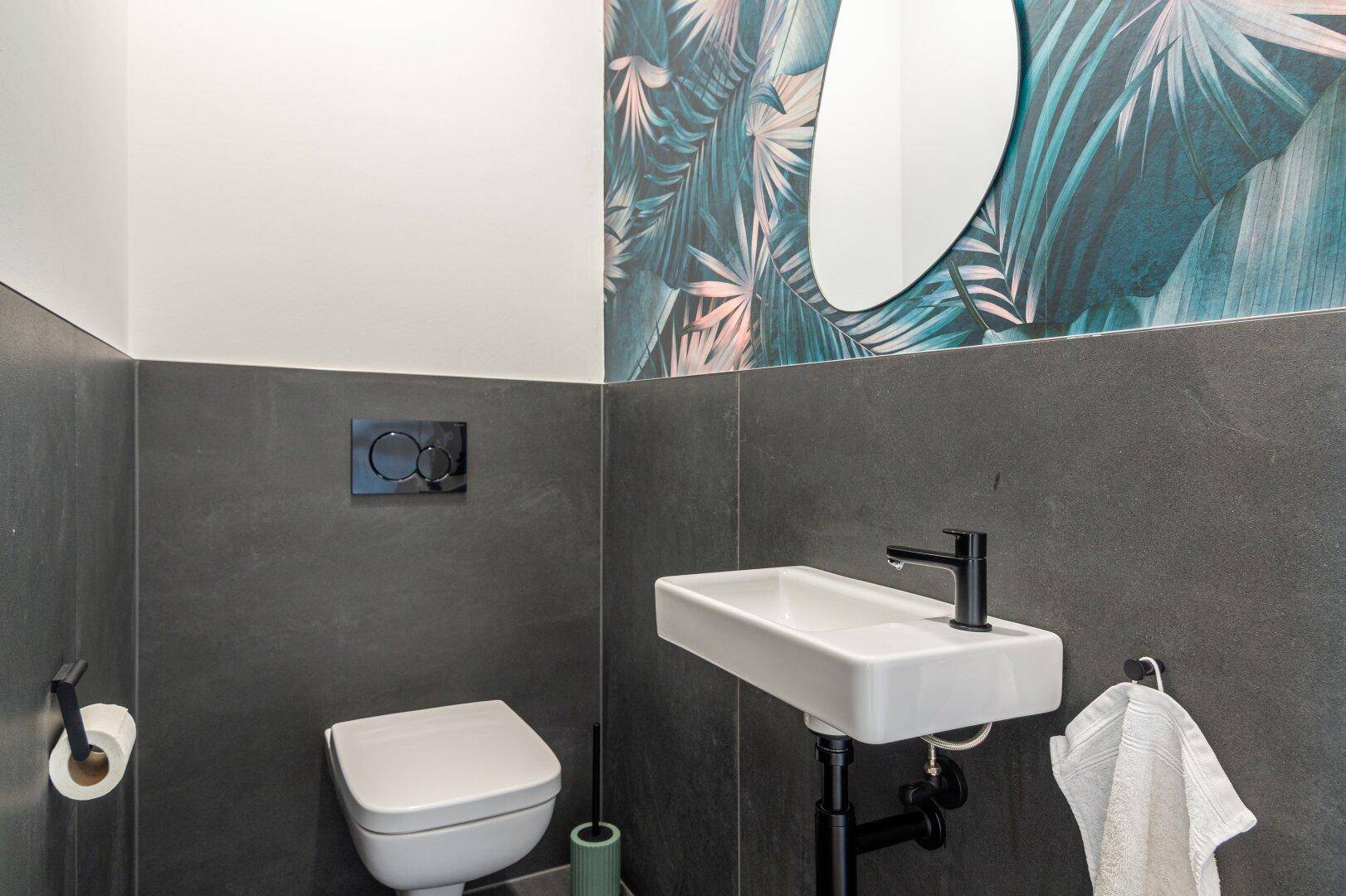 Modernes Gäste-WC mit Wand-WC, kleinem Waschbecken und dekorativer Tapete.