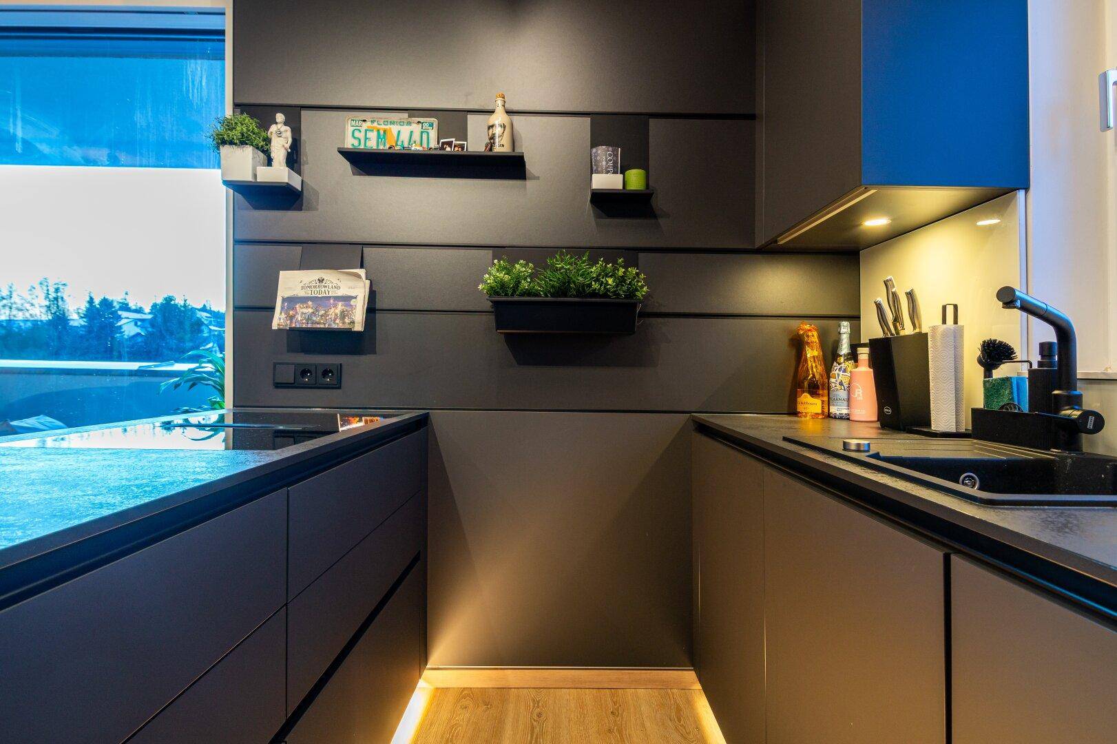 Moderne Einbauküche mit dunklen Schränken, integrierter Beleuchtung und viel Stauraum.