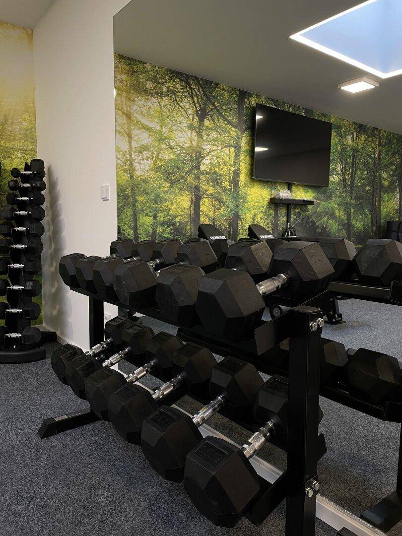 Detailansicht des Fitnessraums mit Hantelregal und großer Spiegelwand.
