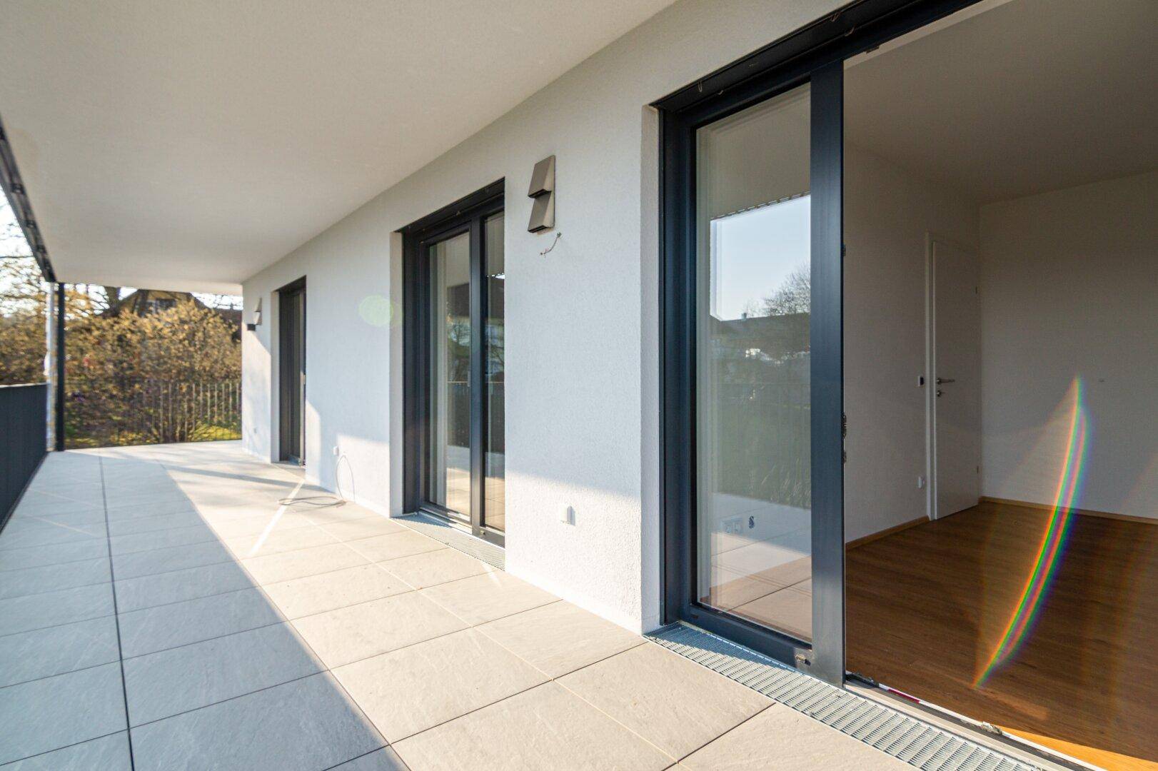 Heller Balkon mit modernen Schiebetüren, die Zugang zu einem lichtdurchfluteten Innenraum bieten.