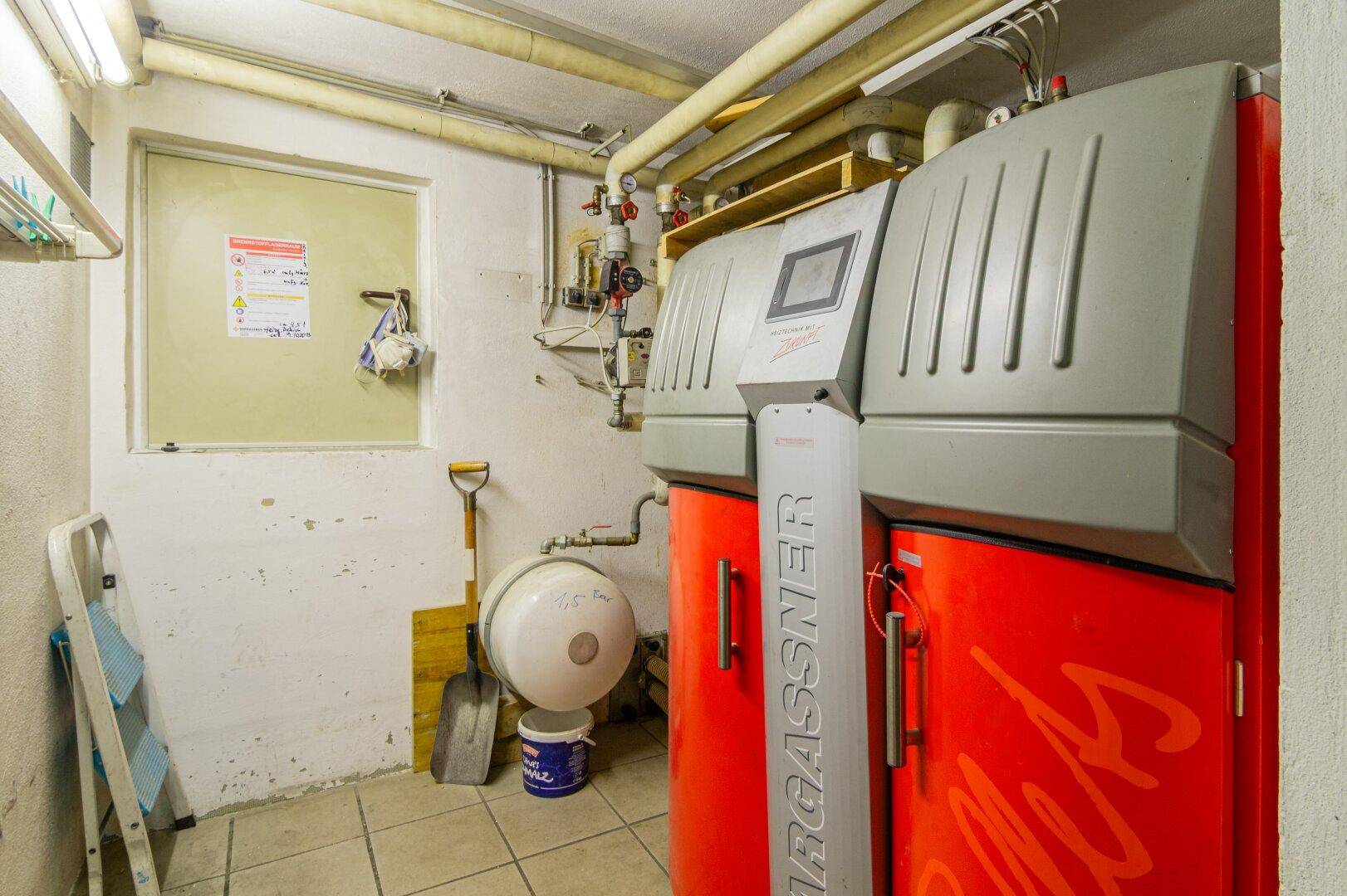 Funktionaler Heizraum im Keller mit großem Heizkessel und Fliesenboden, dient auch als Abstellfläche.