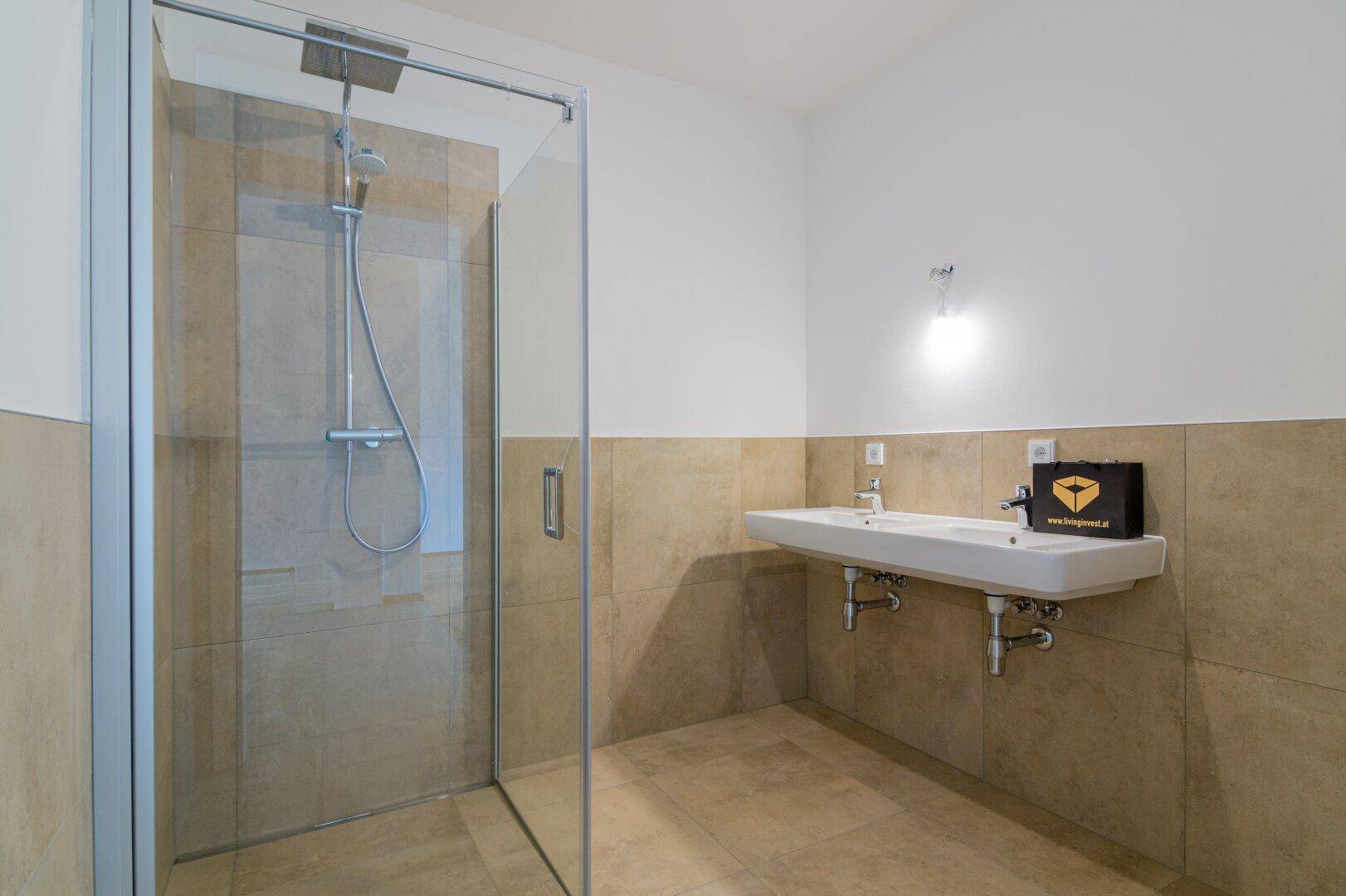 Modernes Badezimmer mit begehbarer Dusche und einem einzelnen Waschbecken, hell gefliest.