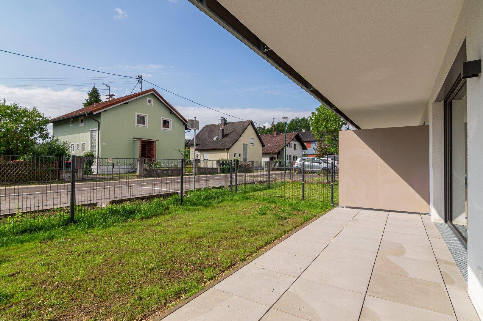 Geräumige, unmöblierte Terrasse mit Blick auf die umliegende Wohngegend und viel Grün.
