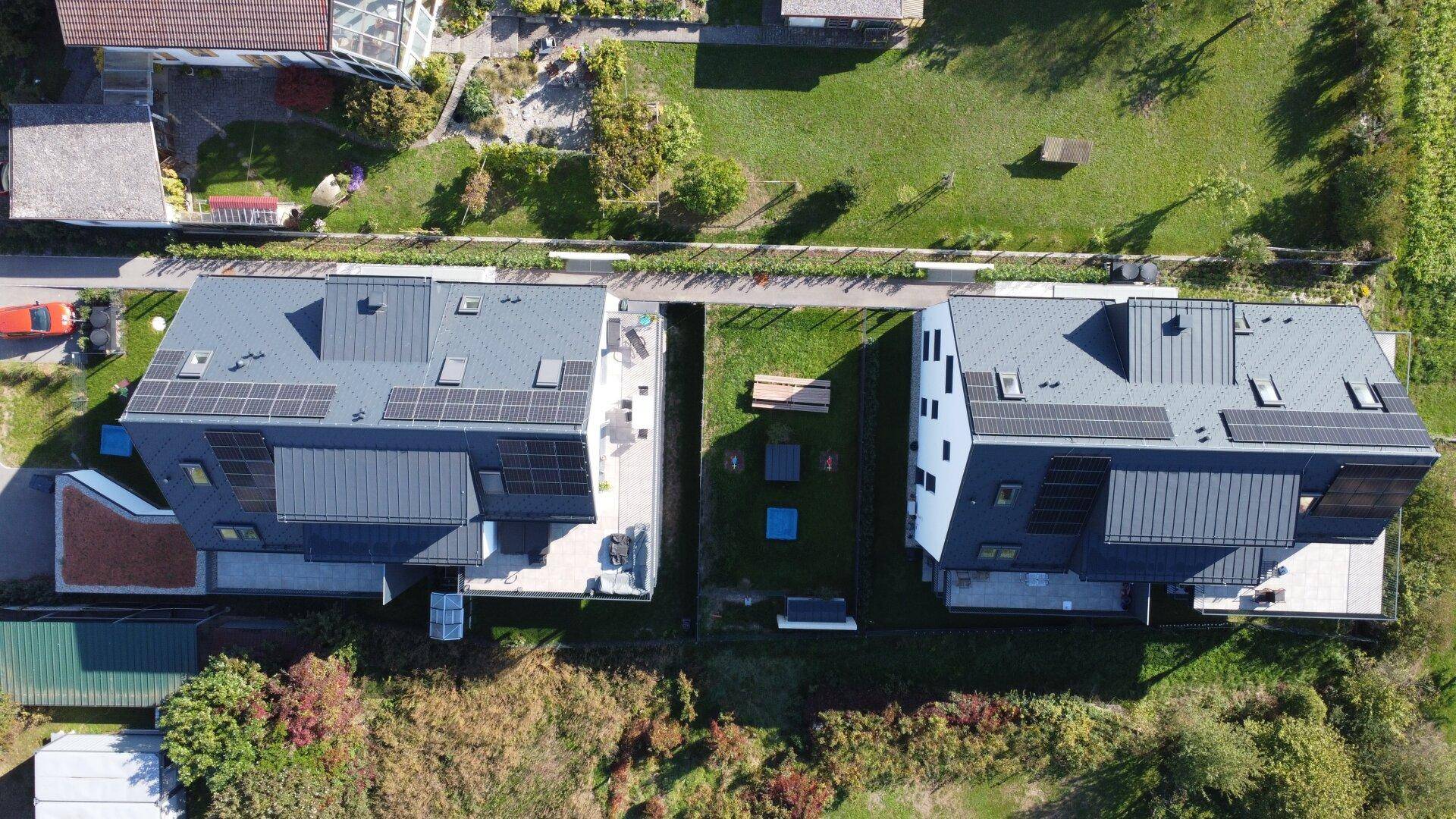 Weitläufige Draufsicht auf zwei moderne Gebäude mit Solaranlagen und umliegenden Grünflächen.