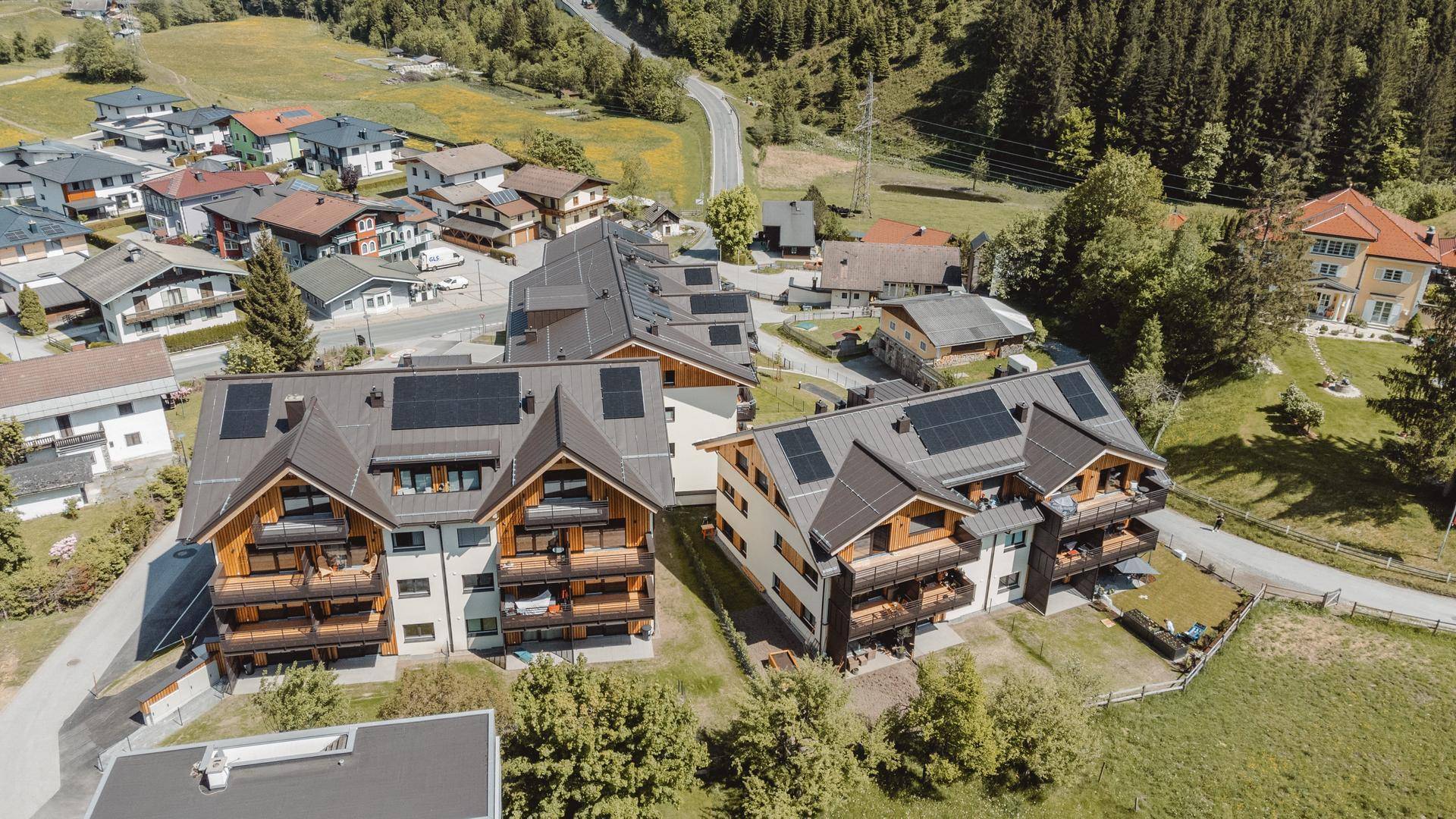 Überblick über die Wohnanlage mit mehreren Gebäuden, Solaranlagen auf den Dächern und viel Grün.