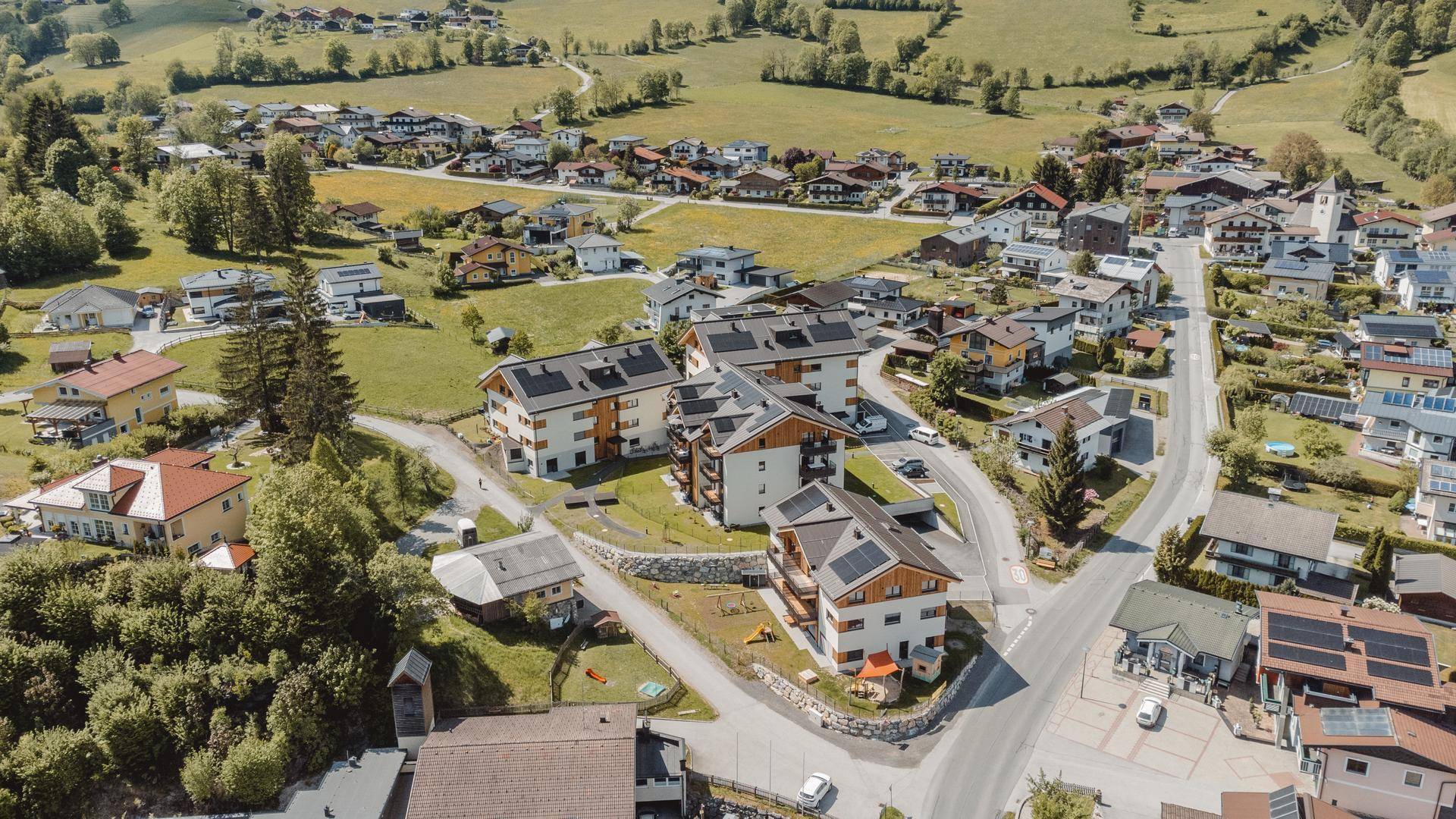 Weitläufige Luftaufnahme einer ländlichen Siedlung mit modernen Gebäuden und grüner Umgebung.