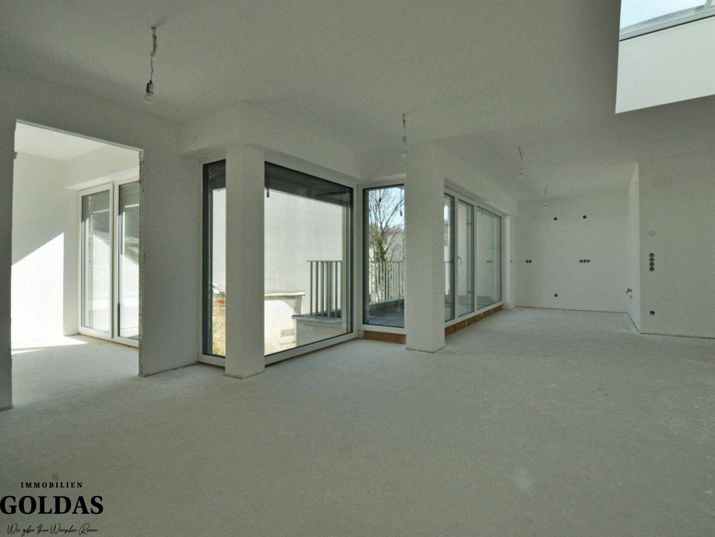 Geräumiger, unmöblierter Innenraum mit großen Fensterfronten und Zugang zu einem Außenbereich.