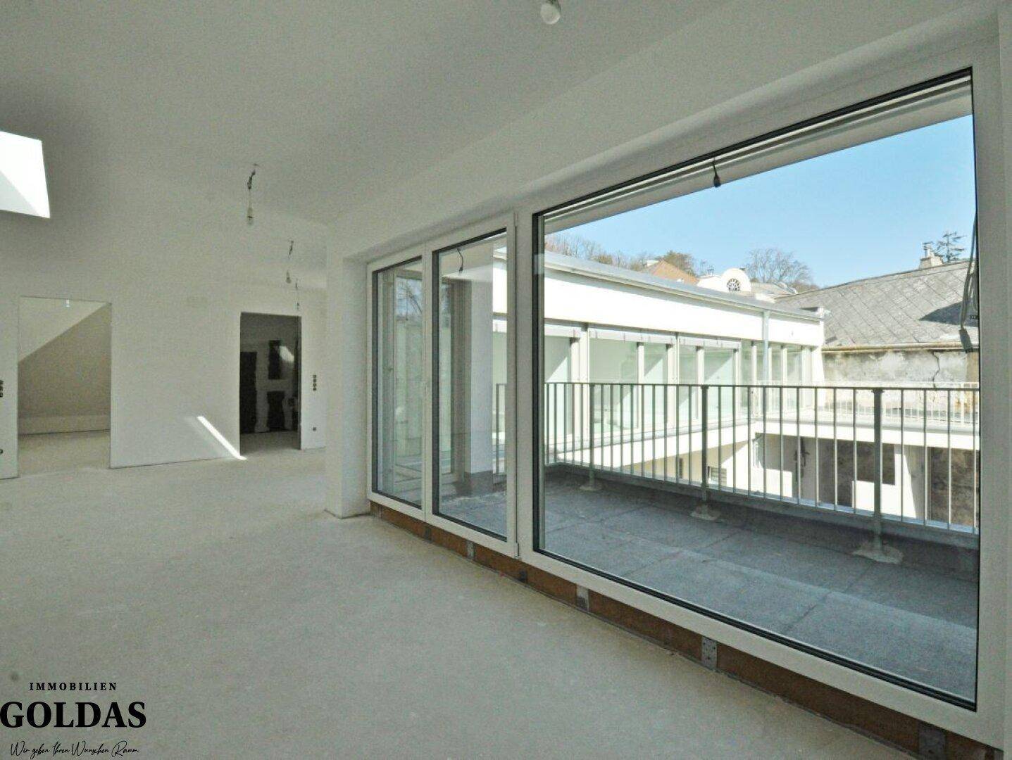 Lichtdurchfluteter Wohnbereich im Rohbau mit breiter Fensterfront und Blick auf den Außenbereich.