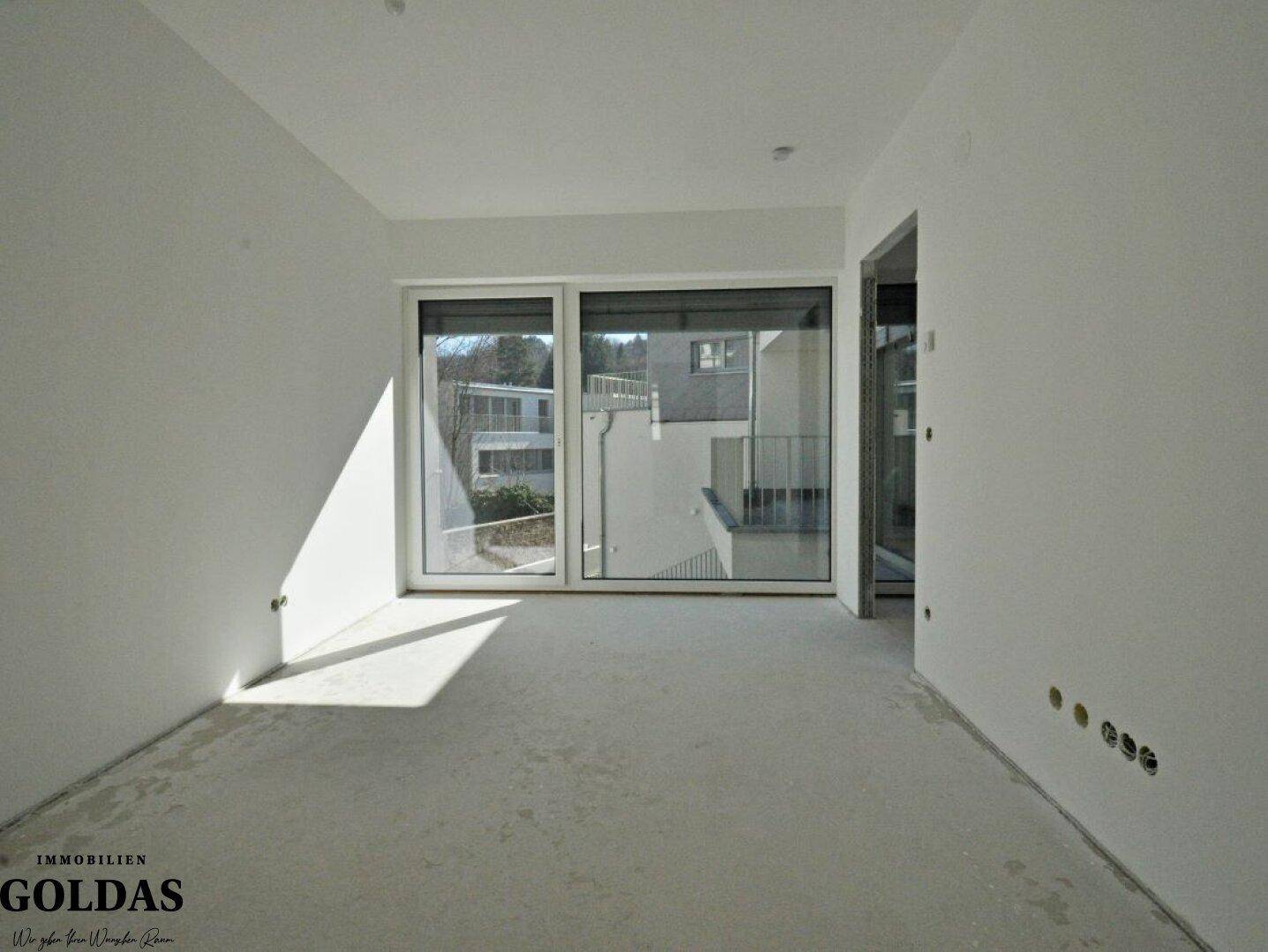 Heller, unmöblierter Raum mit viel Tageslicht durch die breite Fensterfront.
