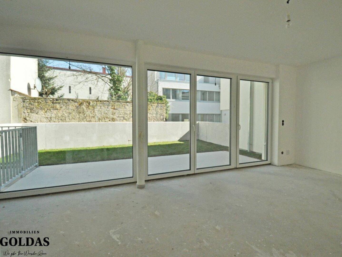 Geräumiger, heller Raum mit großen Schiebetüren und Zugang zur Terrasse und zum Garten.
