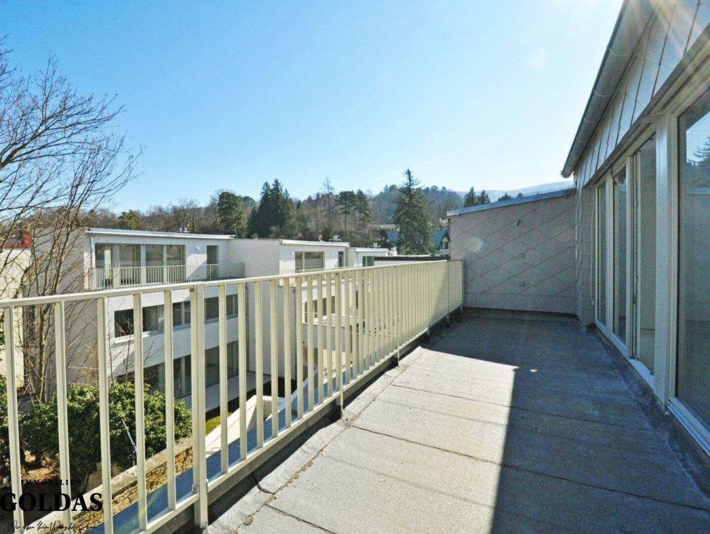 Großer Balkon mit Metallgeländer und weitem Blick über die Umgebung und andere Gebäude.