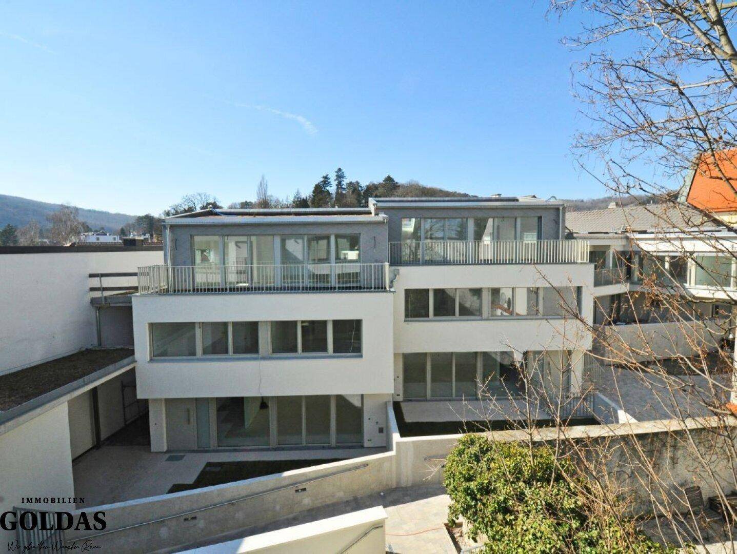 Weitläufige Ansicht des Neubaukomplexes mit mehreren Terrassen und Balkonen in sonniger Lage.