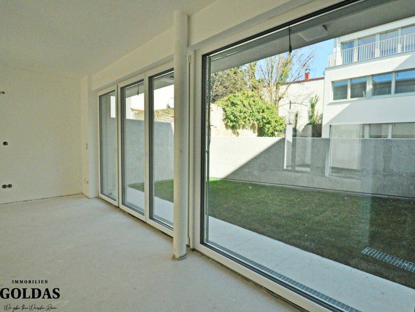 Lichtdurchfluteter Raum mit breiten Fensterfronten, die den Blick auf die Außenanlage freigeben.