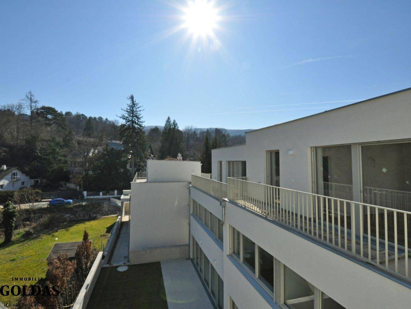 Sonnige Balkone an der modernen Fassade mit weitem Blick auf die umliegende Landschaft und Hügel.