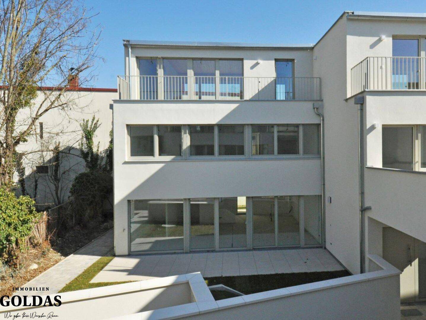 Modernes Wohngebäude mit mehreren Terrassen, Balkonen und einem gepflegten Gartenbereich.