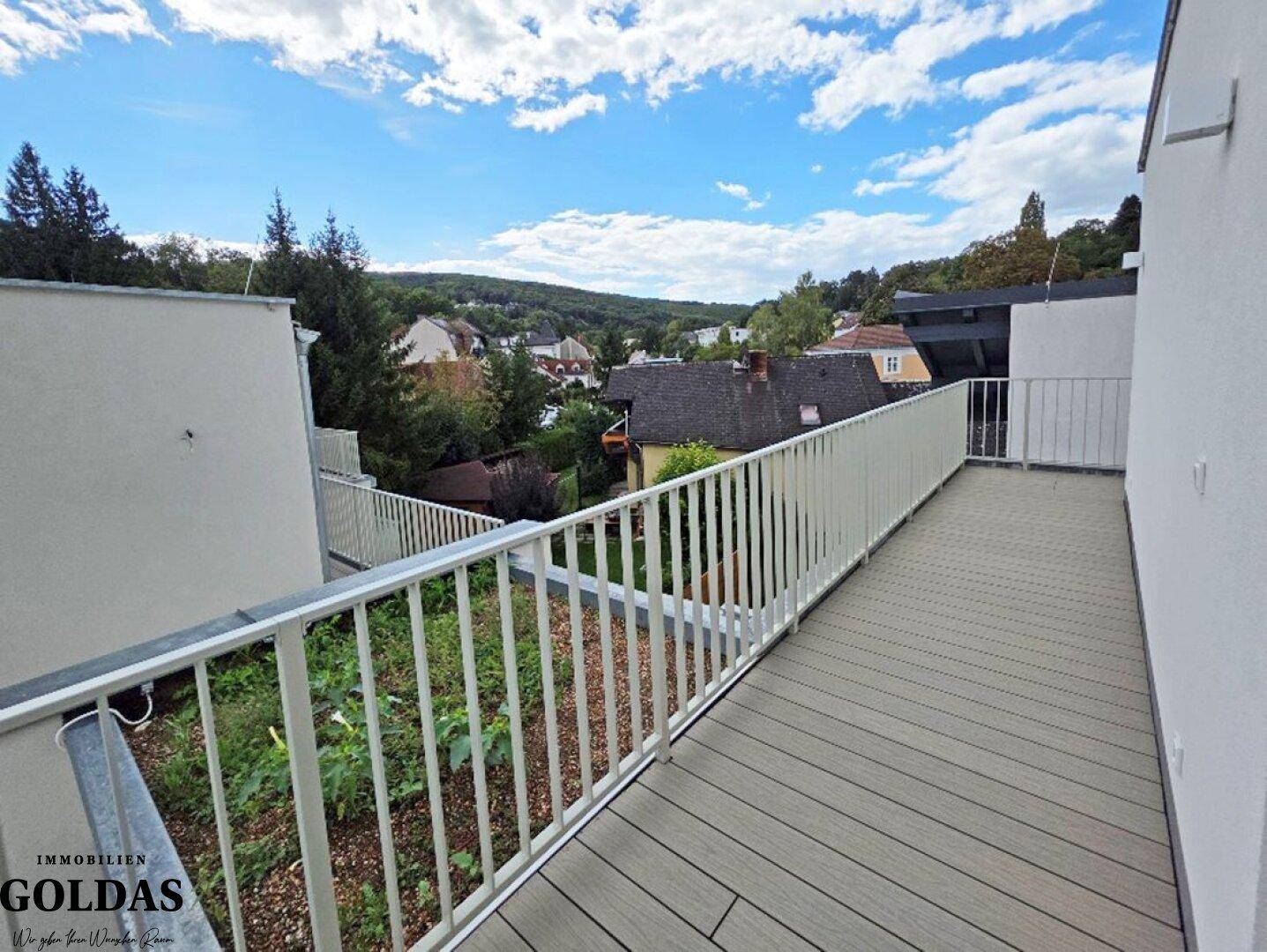Großzügige Dachterrasse mit Holzboden und weitem Blick über die grüne Hügellandschaft.