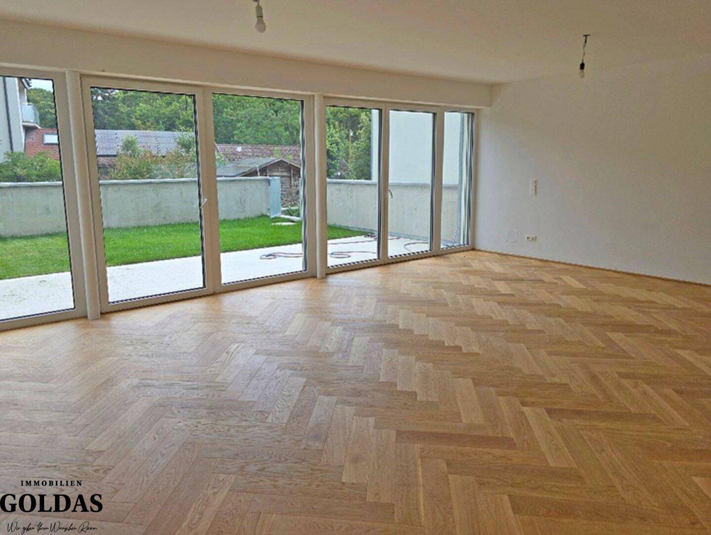 Geräumiges, helles Zimmer mit Fischgrätparkettboden und großen Fenstern mit Zugang zum Garten.