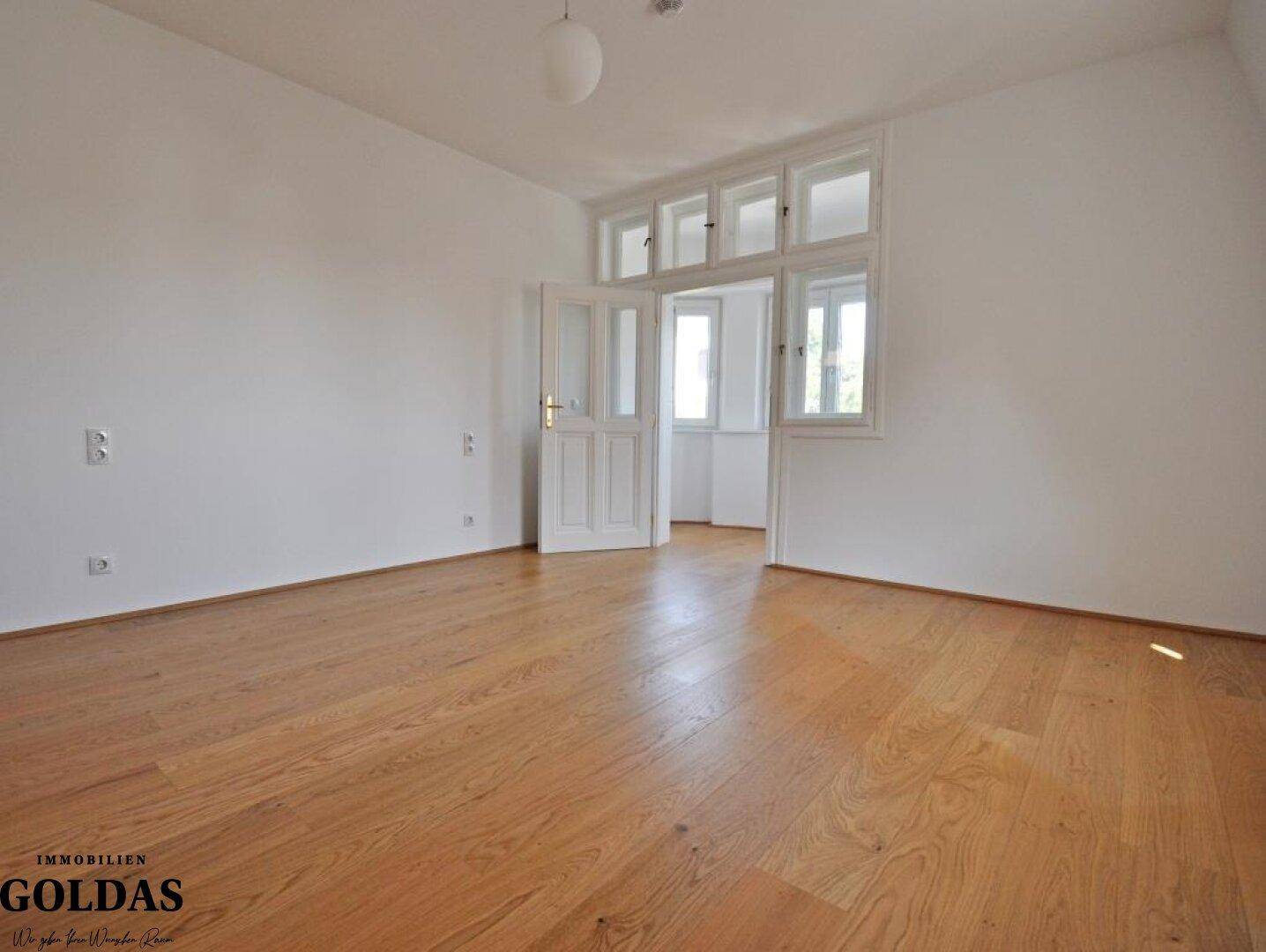 Geräumiges Schlafzimmer mit Holzboden und Fenstern, die viel Tageslicht hereinlassen.
