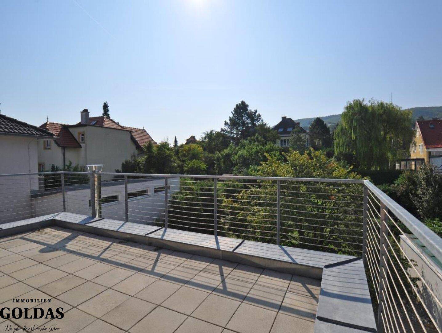 Große Dachterrasse mit Fliesenboden und Metallgeländer, bietet weite Aussicht.