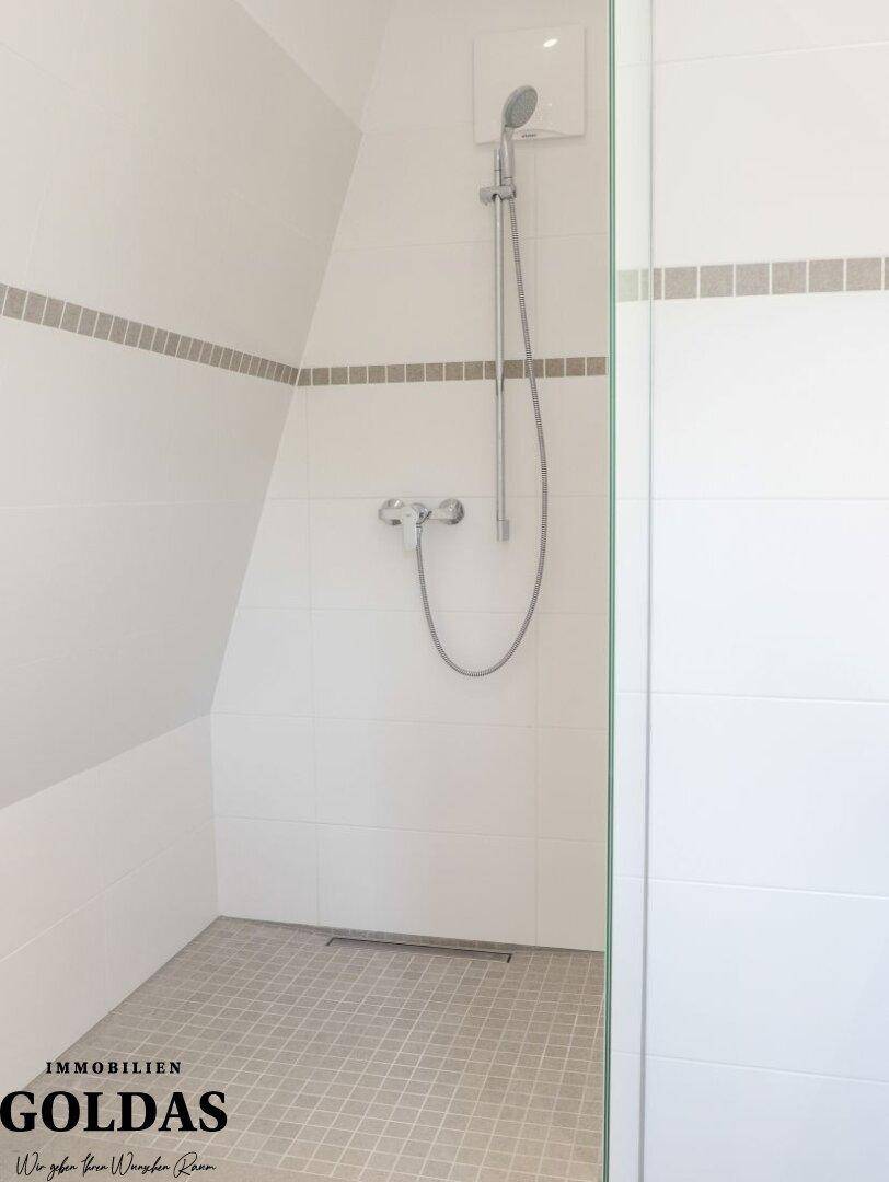 Modernes Badezimmer mit ebenerdiger Dusche und weißen Fliesen im Dachgeschoss.