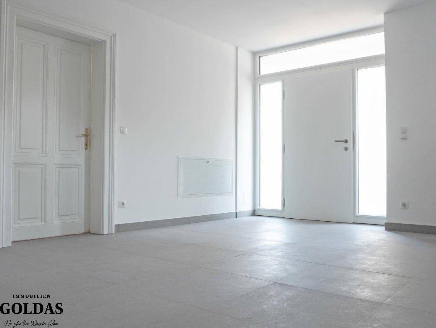 Heller Eingangsbereich mit Fliesenboden und einer modernen Eingangstür mit Seitenlichtern.