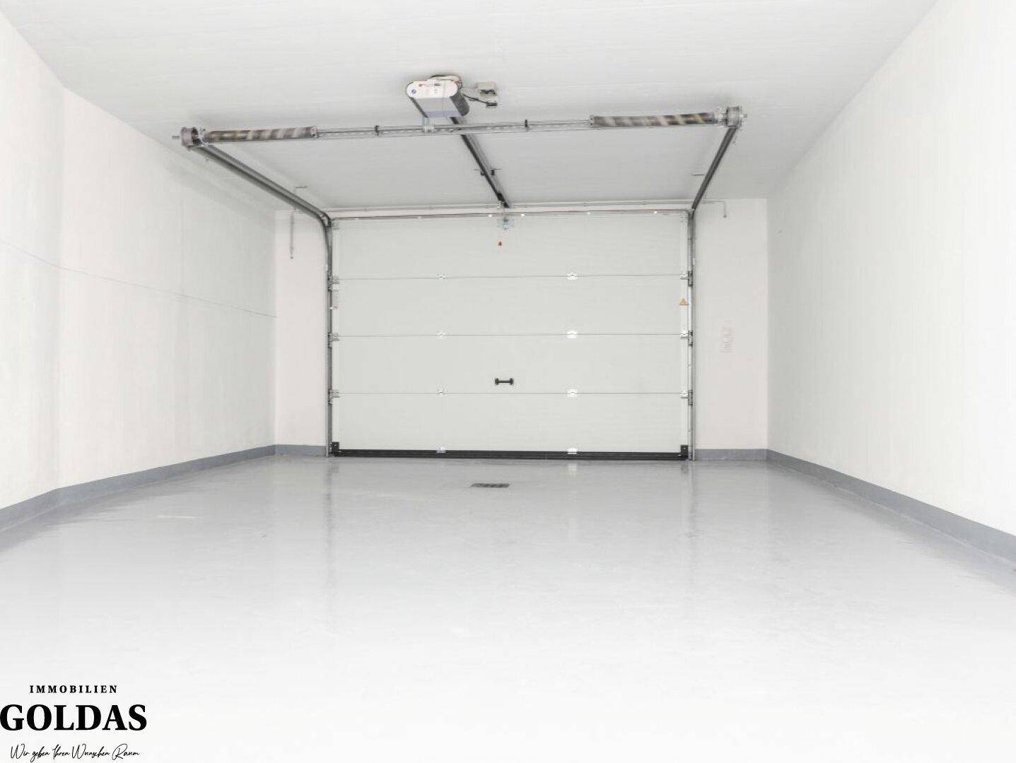 Geräumige Garage mit automatischem Tor und glattem Boden, bietet Platz für Fahrzeuge.