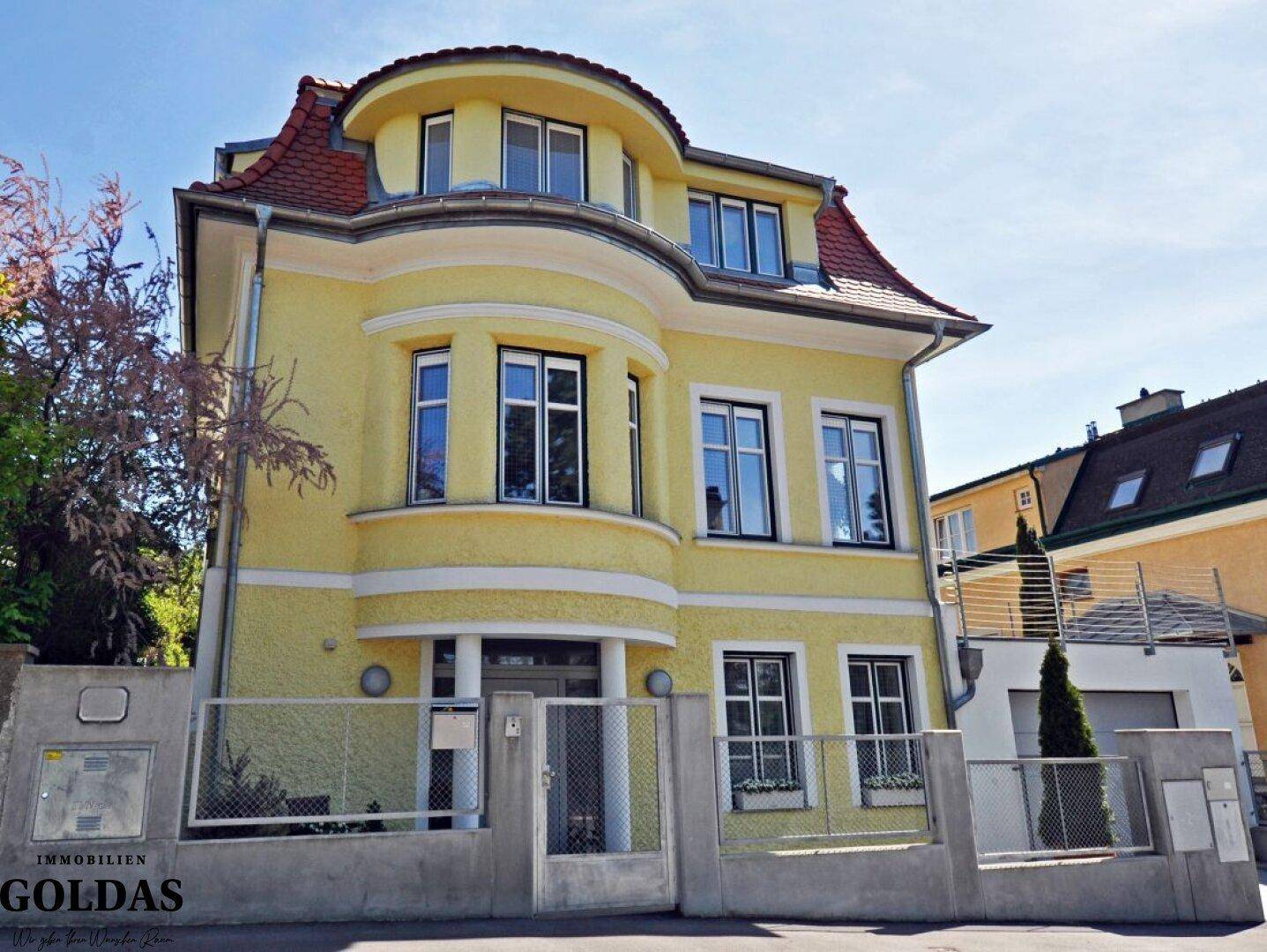 Attraktives Mehrfamilienhaus mit gelber Fassade und klassischer Architektur in sonniger Lage.