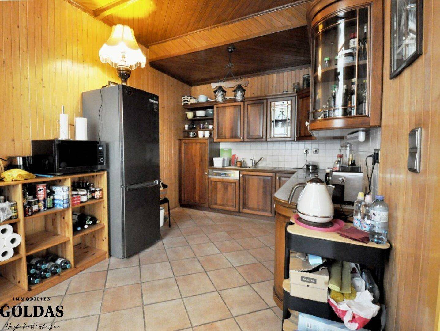 Rustikale Holzküche mit Fliesenboden, Holzwänden und Deckenbalken.