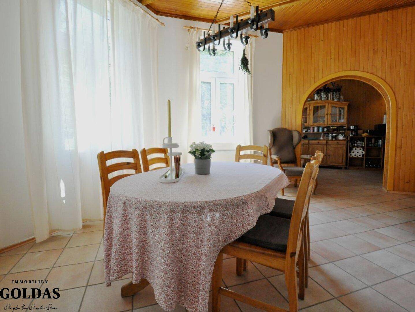 Gemütlicher Essbereich mit Holztisch, Stühlen und Zugang zu einem weiteren Raum.